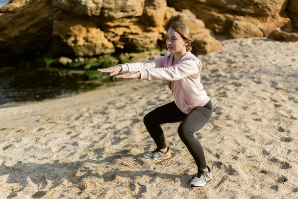 Chica Fitness haciendo ejercicio pierna en la playa - Foto, imagen