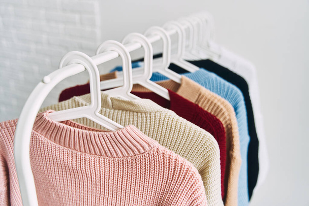 multicolored women's woolen sweaters on hangers. Sale in a fashion store. High quality photo - Photo, Image