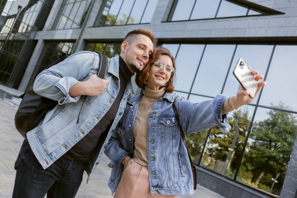 Cute couple of hipster students taking selfie on smartphone in city - Zdjęcie, obraz