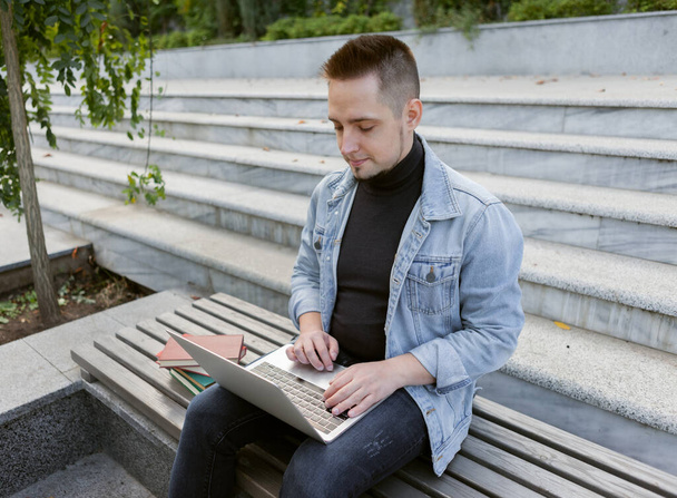 Young student man sitting with laptop. Caucasian man working or study with notebook outdoors. - Φωτογραφία, εικόνα