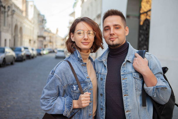 Charismatique couple souriant en vestes denim sur rue urbaine - Photo, image