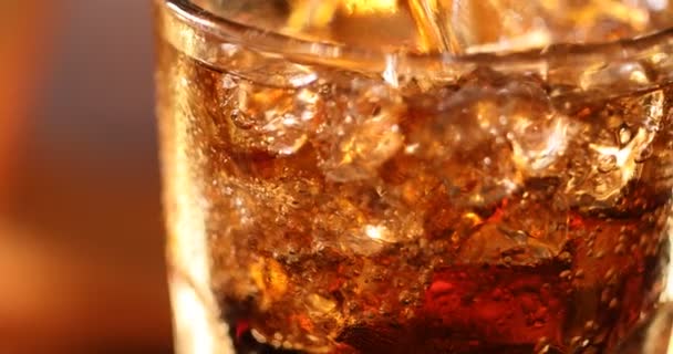 Szklanka Coli z kostkami lodu. Cola pić z lodem i bąbelki w szklanych zbliżeniu. Obracająca się szklanka napoju Cola na rozmytym tle. Powolny ruch obracający się wokół materiału wideo 4K - Materiał filmowy, wideo