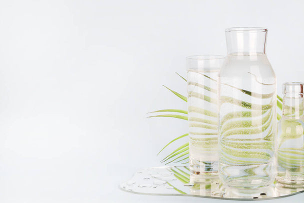 пальмовый лист, искажённый через воду в стекле и бутылки с зеркалом на синем фоне. Home decor, eco friendly, pure water, gardening concept.copy space - Фото, изображение