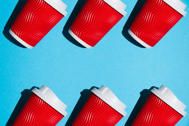 Pastterna, diverse tazze di carta rossa per il caffè o il tè per andare su uno sfondo blu. Stoviglie usa e getta su uno sfondo colorato con spazio di copia. - Foto, immagini