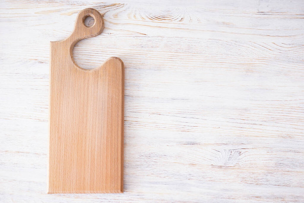 Wooden cutting board on wooden background, space for text. Flat lay. - Photo, Image