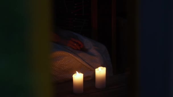 Погашение свечей. Женщина в белом платье сидит на коленях возле зажженных свечей. Она задувает свечи.. - Кадры, видео