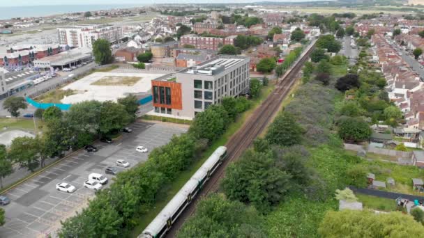 Légi felvétel Shoreham-by-Sea városáról, egy tengerparti városról és kikötőről Nyugat-Sussex-ben (Anglia), amely egy vasúti síneken közlekedő vonatot mutat be egymás melletti lakótelepek és üzletek mentén - Felvétel, videó