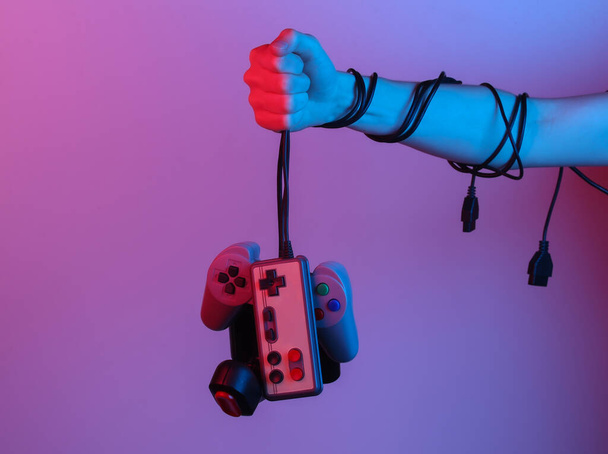 Manos sosteniendo joystick retro por cable en luz gradiente de neón azul-rojo. Viejos juegos. Ola retro de los 80. Minimalismo - Foto, Imagen