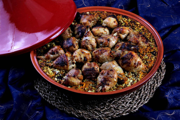 Plato bereber tradicional tajino hecho con patas de pollo, cuscús o arroz, fondo de tela azul - Foto, imagen