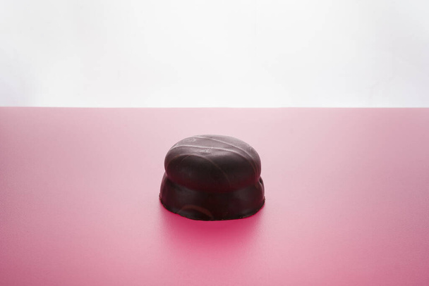 Biscuit cookie in chocolate glaze or frosting on pink background. Sweet tasty unhealthy snack. - Photo, Image