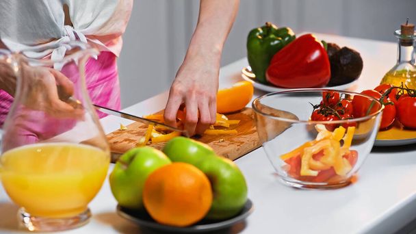 partial view of woman cutting bell pepper on chopping board - Foto, Imagen