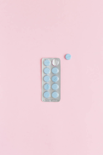 Läpipainopakkaus, jossa on sinisiä pillereitä vaaleanpunaisella taustalla, ylhäältä katsottuna. Lääketieteellinen käsite, tausta.  - Valokuva, kuva