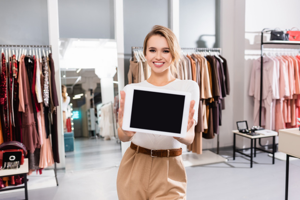 vendedor alegre segurando tablet digital com tela em branco em primeiro plano desfocado no showroom  - Foto, Imagem