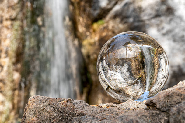 Reflectie van waterval in kristallen lensbal. - Foto, afbeelding
