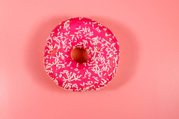 Смачний рожевий пончик на рожевому фоні
 - Фото, зображення