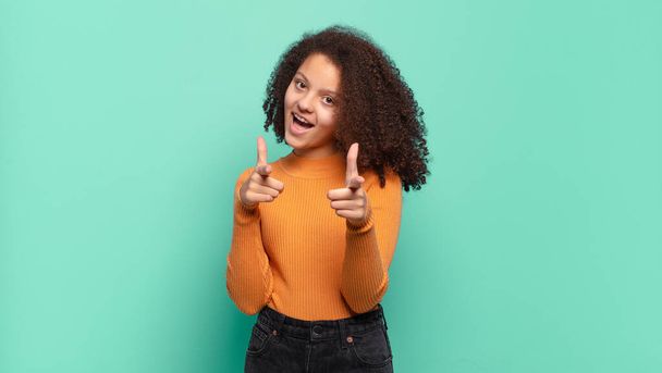 Girl smiling with a positive, successful, happy attitude pointing to the camera, making gun sign with hands - Photo, image