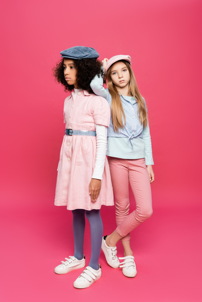 stylish girl leaning on shoulder of african american friend while posing on pink - Foto, Bild