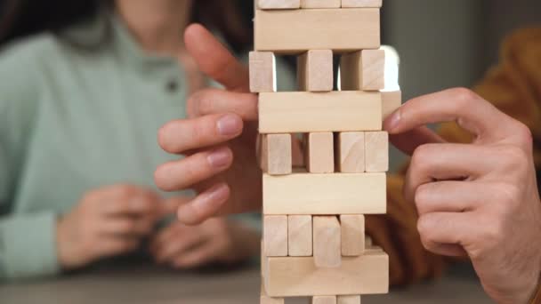 of male hands pulling wooden block of jenga game. Tower made of wooden blocks and human hands take one block - Footage, Video