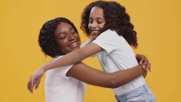 Mutlu Afrikalı Amerikalı kız ve kadın kucaklaşıyorlar, sarılıyorlar, turuncu arka planda. - Video, Çekim
