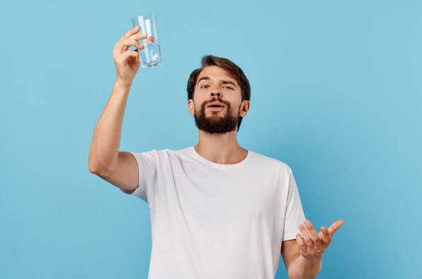 guy with a glass of water on a blue background lifestyle white t-shirt cropped view - Fotografie, Obrázek