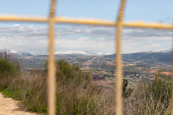 İsrail ve Lübnan sınırındaki kapalı metal bir kapıdan İsrail 'in kuzeyindeki Misgav Am köyüne doğru Lübnan' a bakın. - Fotoğraf, Görsel