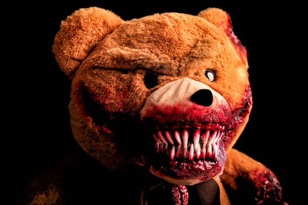 Страшний ведмідь з моторошною кривавою усмішкою на чорному тлі. Іграшка жахів. Хеллоуїн концепція. розрізана лапа і трохи укушене вухо в крові
 - Фото, зображення