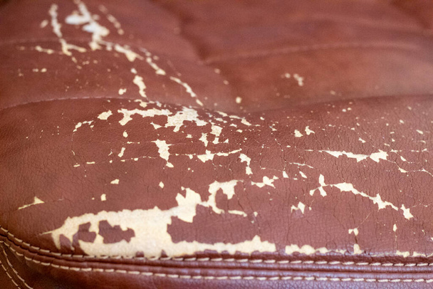 Der Hintergrund der abgenutzten Lederpolsterung des Stuhls ist Nahaufnahme. Die Textur der abgenutzten Lederpolster - Foto, Bild