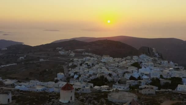 Lennokki kuvaa ihmisiä katsomassa kaunista auringonlaskua Amorgosissa, Kreikassa. Lennokki lähtee, ja näet pienen kylän alla. 1080p - Materiaali, video