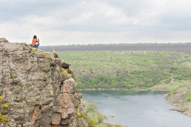 Young couple sitting on a steep rocky cliff - Photo, Image