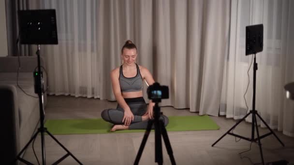 concetto di sport e vlogging donna o blogger con fotocamera su treppiede registrare lezione di yoga online a casa. Studio video a casa. Luce LED e fotocamera su treppiede. - Filmati, video
