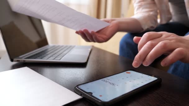 Mujer utiliza calculadora en el teléfono celular para contar grandes pagos - Imágenes, Vídeo