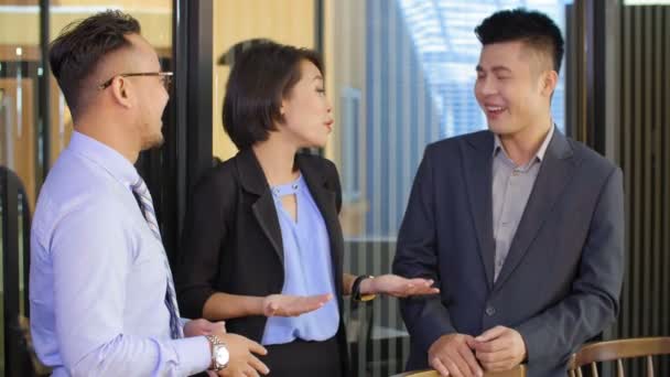 Medium shot of two Asian businessmen and businesswoman standing and having talk - Footage, Video
