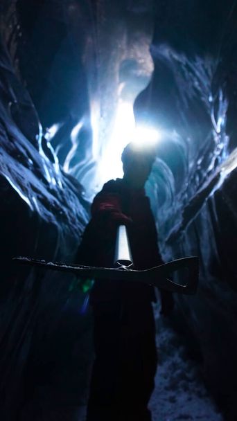 Horolezec s sekáčkem na led stojí u východu z jeskyně - Fotografie, Obrázek