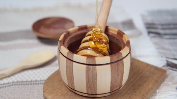 Gezonde biologische Dikke honing druipend van de houten honinglepel, close-up. zoet dessert achtergrond. - Video