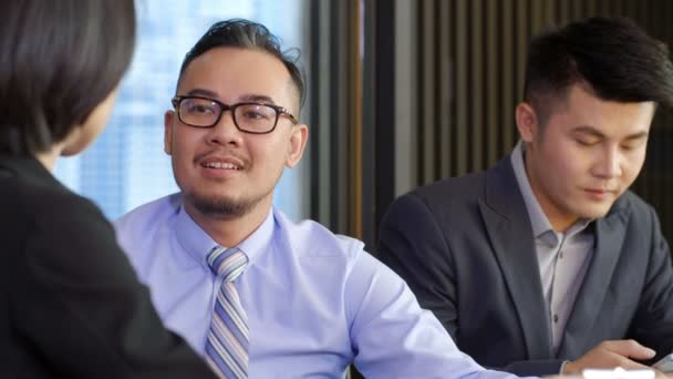 Средний снимок азиатского бизнесмена и бизнесвумен разговаривают в то время как их коллега-мужчина с помощью смартфона - Кадры, видео