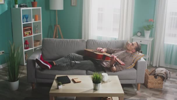 Junger Mann entspannt sich mit Gitarrenspiel - Filmmaterial, Video