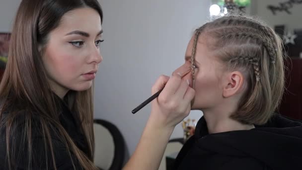 Γυναίκα κάνει μακιγιάζ για ελκυστική ξανθιά γυναίκα μαλλιά στο στούντιο. Βίντεο του καλλιτέχνη μακιγιάζ εφαρμογή καλλυντικών για όμορφο μοντέλο - Πλάνα, βίντεο