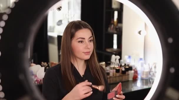 Profession make up artist woman reviewing beauty products on a video blog at beauty studio. Woman use ring lamp - Footage, Video