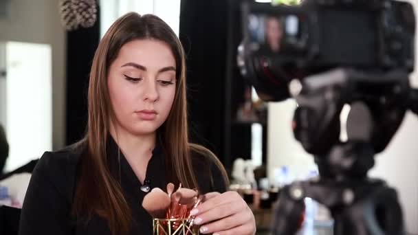 Jonge mooie vrouw en professionele schoonheid make-up kunstenaar blogger opnemen van make-up tutorial in de studio te delen op de website of sociale media. Focus op het model - Video