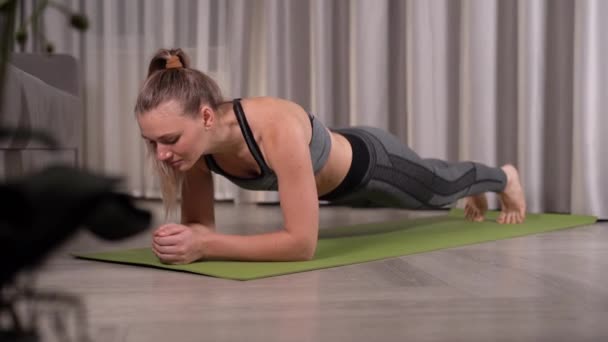 izmos nő gyakorolja a fitnesz szőnyegen a tornateremben. Sportos nő csinál hasi gyakorlatok edzés közben otthon. - Felvétel, videó