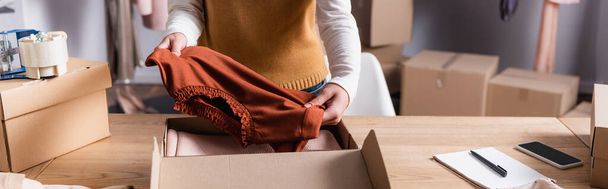 partial view of showroom owner holding sweater near carton box, banner - Photo, Image