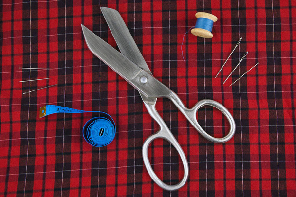 https://cdn.create.vista.com/api/media/small/453132624/stock-photo-sewing-tools-large-scissors-meter-thread-needles-lying-checkered-red
