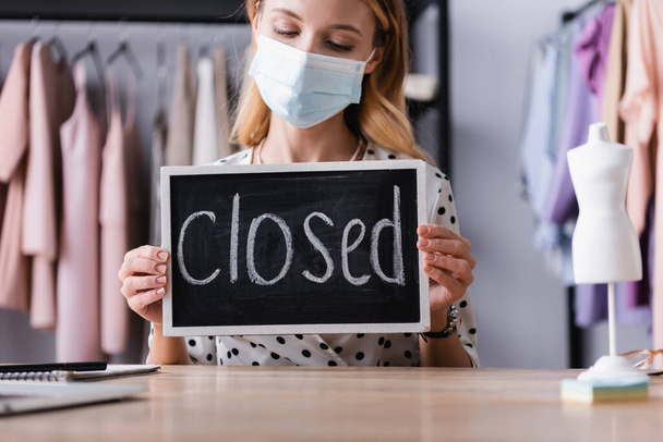 proprietário showroom em máscara médica, segurando placa com letras fechadas em primeiro plano borrado - Foto, Imagem