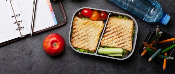Healthy lunch box with sandwich and vegetables, apple and water bottle on office table. Top view flat lay - Photo, Image