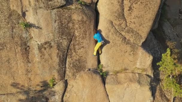 Luchtfoto van een jongeman klimt voorzichtig over een rotsspleet - Video