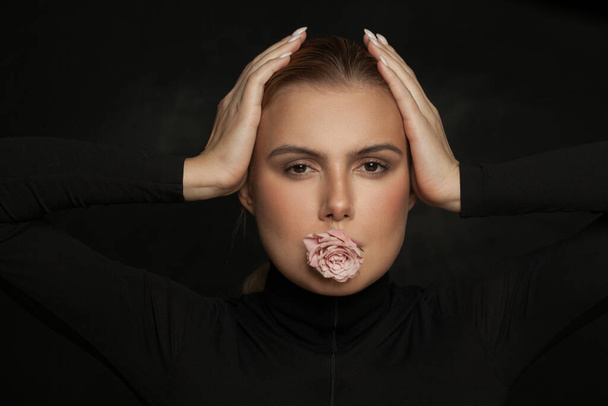 Όμορφη συναισθηματική γυναίκα με τριαντάφυλλο λουλούδι σε μαύρο φόντο - Φωτογραφία, εικόνα