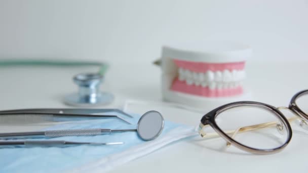 Oikomishoidon hampaiden malli ja ammatillinen hammaslääkäri työkaluja pöydälle hammaslääkärin toimistossa - Materiaali, video