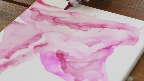 Κοντινό πλάνο του καλλιτέχνη γυναίκα ζωγραφίζει μια αφηρημένη εικόνα, χύνει ένα ροζ σωλήνα χρώμα fron σε βρεγμένα κανάλια - Πλάνα, βίντεο