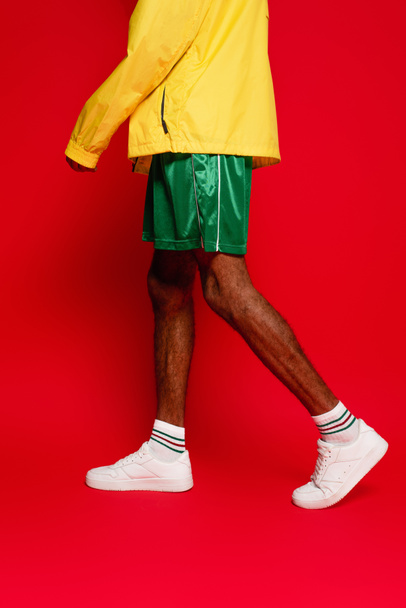 обрезанный вид на стильный африканский американец, идущий по красному - Фото, изображение