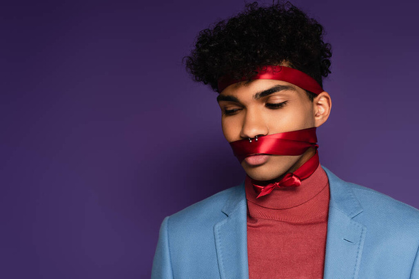 jong Afrikaans amerikaans man gebonden met rood lint op paars  - Foto, afbeelding